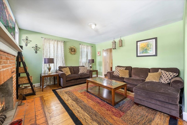 living room featuring a brick fireplace, baseboards, and hardwood / wood-style floors