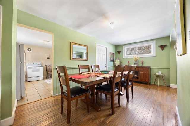 dining space featuring a wainscoted wall and light wood-style flooring