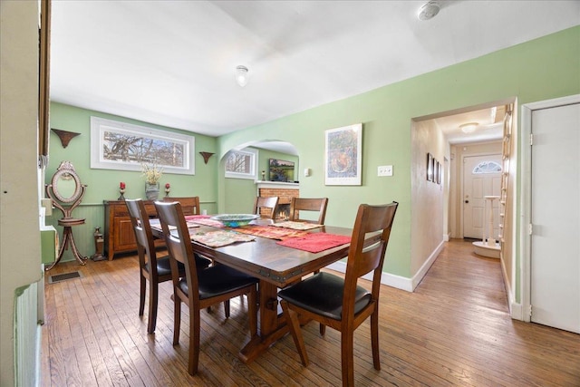 dining area with light wood-style floors, visible vents, arched walkways, and baseboards