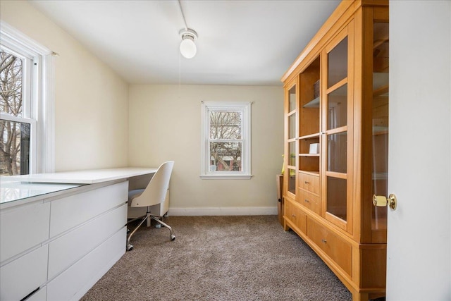 carpeted home office with built in desk and baseboards