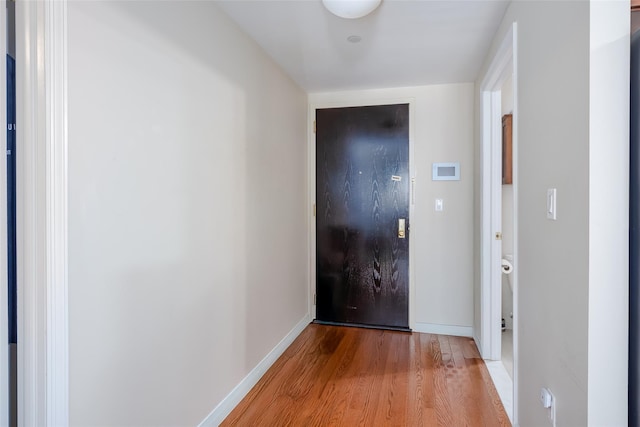 hall with light wood-style flooring and baseboards