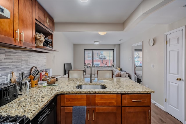 kitchen featuring black dishwasher, light stone counters, decorative backsplash, a peninsula, and a sink