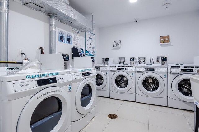 community laundry room with light tile patterned floors and washer and clothes dryer