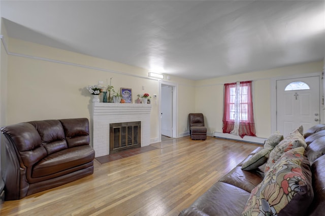 living room featuring a fireplace, a baseboard radiator, and wood finished floors