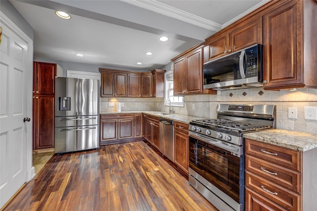 kitchen with light stone counters, appliances with stainless steel finishes, a sink, and dark wood finished floors