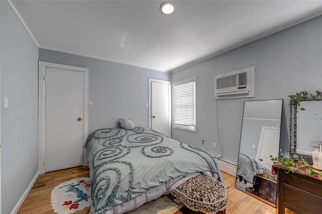 bedroom with light wood-style floors, an AC wall unit, a baseboard heating unit, and crown molding