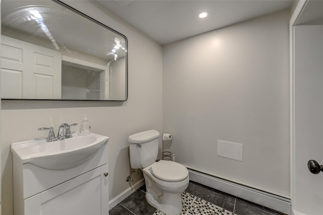 half bathroom with toilet, vanity, baseboards, baseboard heating, and tile patterned floors