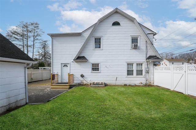 back of house featuring a yard, a gate, a fenced backyard, and a gambrel roof