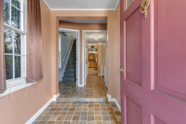 foyer entrance with ornamental molding, baseboards, and stairs