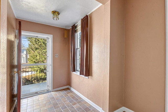 entryway with a wealth of natural light, a textured wall, and baseboards