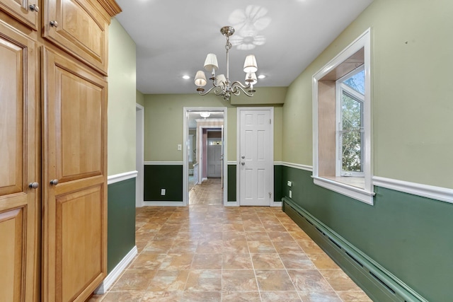 hallway featuring a baseboard heating unit, baseboards, and an inviting chandelier