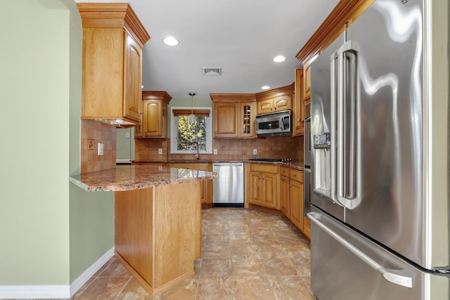 kitchen featuring decorative backsplash, appliances with stainless steel finishes, light stone counters, decorative light fixtures, and a peninsula