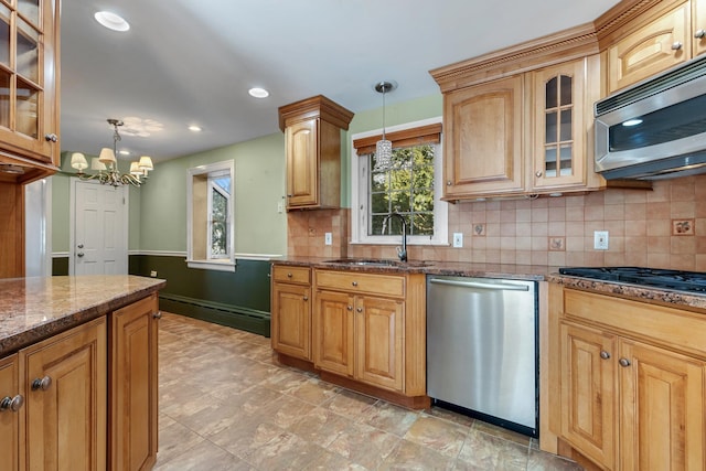 kitchen with pendant lighting, stainless steel appliances, a baseboard radiator, a sink, and dark stone countertops