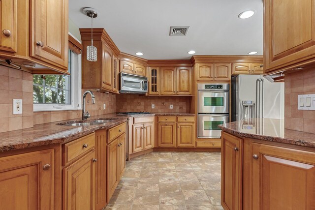 kitchen with visible vents, appliances with stainless steel finishes, brown cabinetry, and a sink