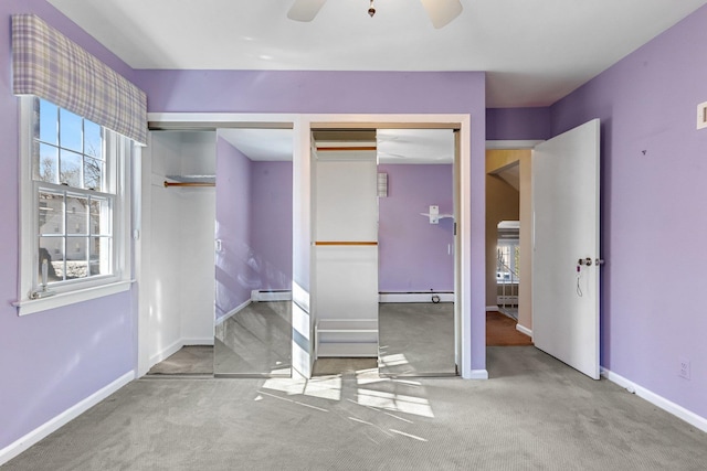 unfurnished bedroom with baseboards, a ceiling fan, a baseboard radiator, carpet, and two closets