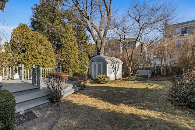 view of yard with a wooden deck, fence, a storage unit, and an outdoor structure