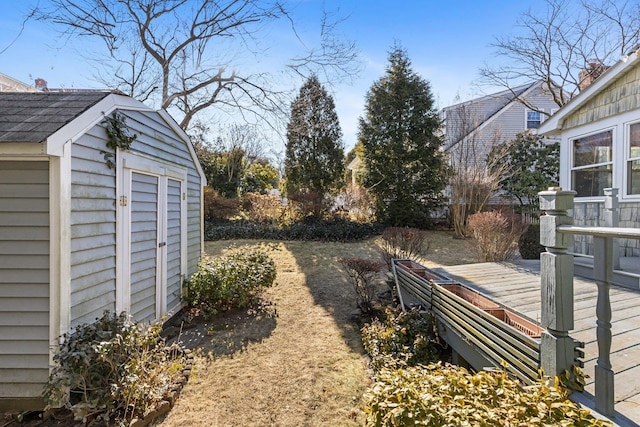 view of yard with a storage shed, a deck, and an outbuilding