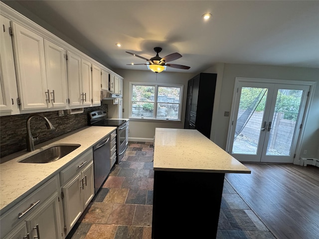 kitchen with under cabinet range hood, a sink, a center island, appliances with stainless steel finishes, and decorative backsplash