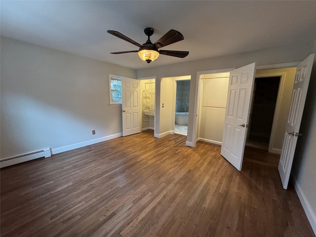 unfurnished bedroom with dark wood-type flooring, baseboard heating, baseboards, and ensuite bathroom