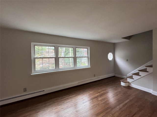 unfurnished room featuring wood finished floors, baseboards, baseboard heating, and stairs