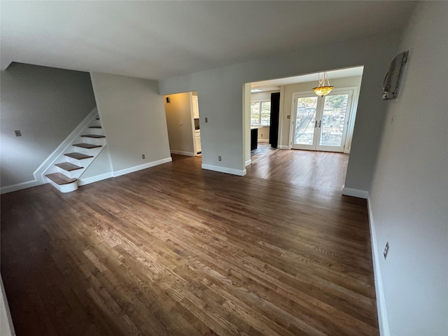 unfurnished living room featuring french doors, dark wood finished floors, stairway, and baseboards