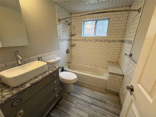 full bathroom with tile walls, vanity, toilet, and shower / bathtub combination