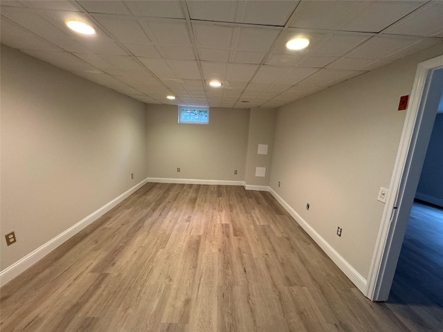 basement with a paneled ceiling, recessed lighting, baseboards, and wood finished floors