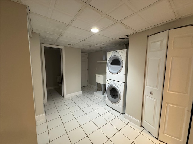 laundry room featuring laundry area, light tile patterned floors, baseboards, and stacked washer / drying machine