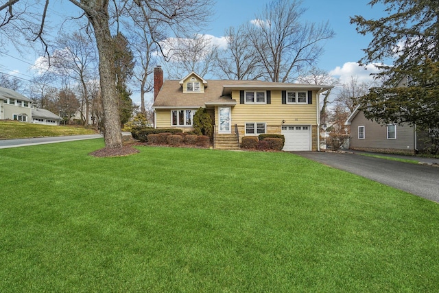 view of front of home featuring aphalt driveway, a garage, a chimney, and a front lawn