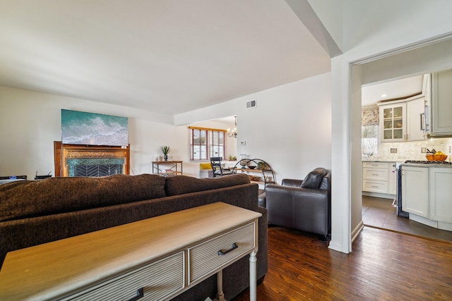 living room with a chandelier, a high end fireplace, visible vents, and dark wood finished floors