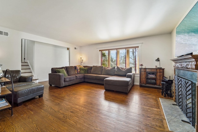 living area featuring stairway, a fireplace with flush hearth, visible vents, and wood finished floors