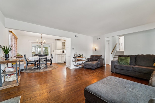 living area with a notable chandelier, stairs, visible vents, and dark wood-style flooring