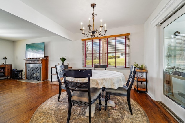 dining space featuring a notable chandelier, a fireplace with flush hearth, baseboards, and wood finished floors