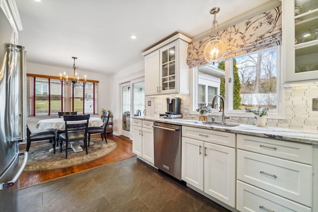 kitchen featuring light stone countertops, appliances with stainless steel finishes, backsplash, and decorative light fixtures