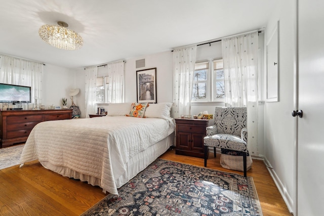 bedroom with wood finished floors, visible vents, and baseboards