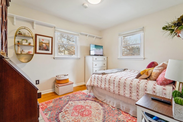 bedroom with multiple windows, baseboards, and wood finished floors