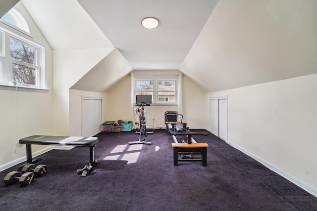 exercise room featuring vaulted ceiling and baseboards