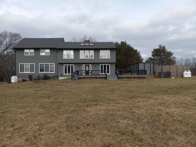 rear view of property with a wooden deck and a yard