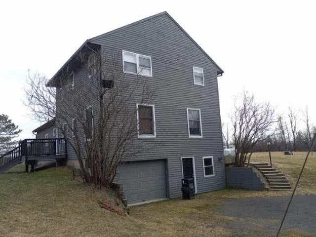 back of house featuring driveway, stairs, and a yard