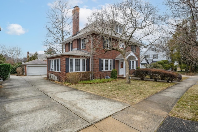 american foursquare style home with an outbuilding, brick siding, a detached garage, a chimney, and a front yard