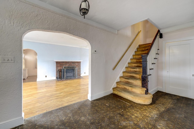 interior space featuring arched walkways, a textured wall, a fireplace, baseboards, and tile patterned floors