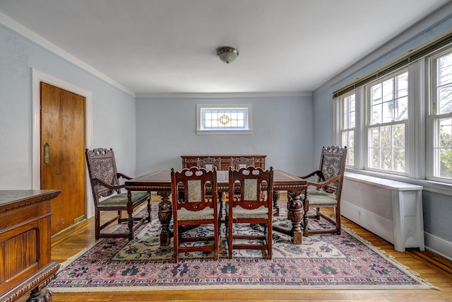 dining space featuring baseboards, wood finished floors, and ornamental molding