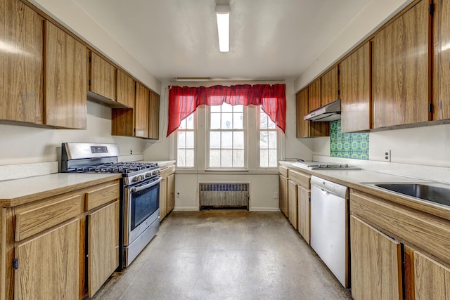 kitchen with under cabinet range hood, baseboards, light countertops, appliances with stainless steel finishes, and radiator