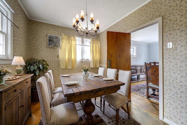 dining room with ornamental molding, an inviting chandelier, light wood-style floors, and wallpapered walls