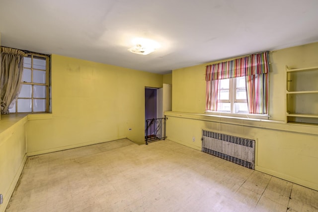 spare room featuring radiator and tile patterned floors