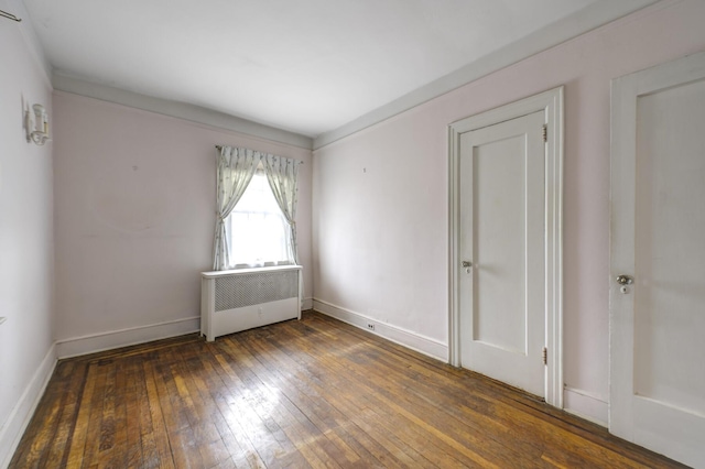 spare room featuring radiator, wood-type flooring, and baseboards