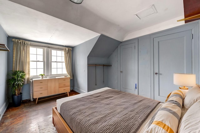 bedroom featuring attic access, lofted ceiling, baseboards, and wood finished floors