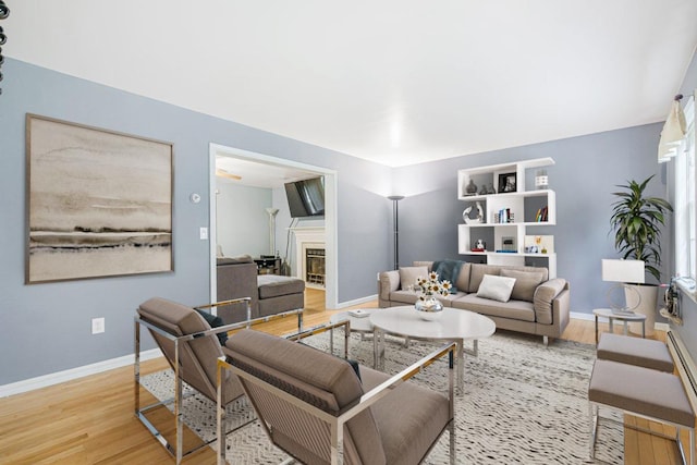 living room featuring baseboards, wood finished floors, and a glass covered fireplace