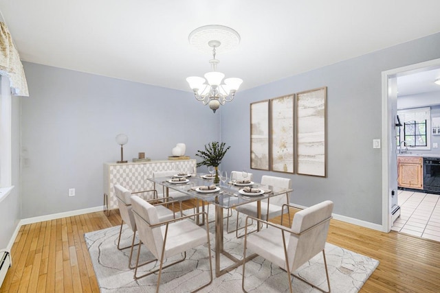 dining space featuring a chandelier, light wood-type flooring, a baseboard heating unit, and baseboards