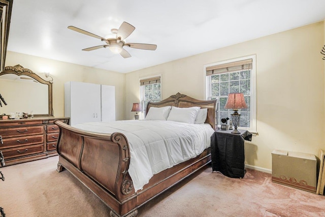 bedroom featuring light carpet, ceiling fan, multiple windows, and baseboards